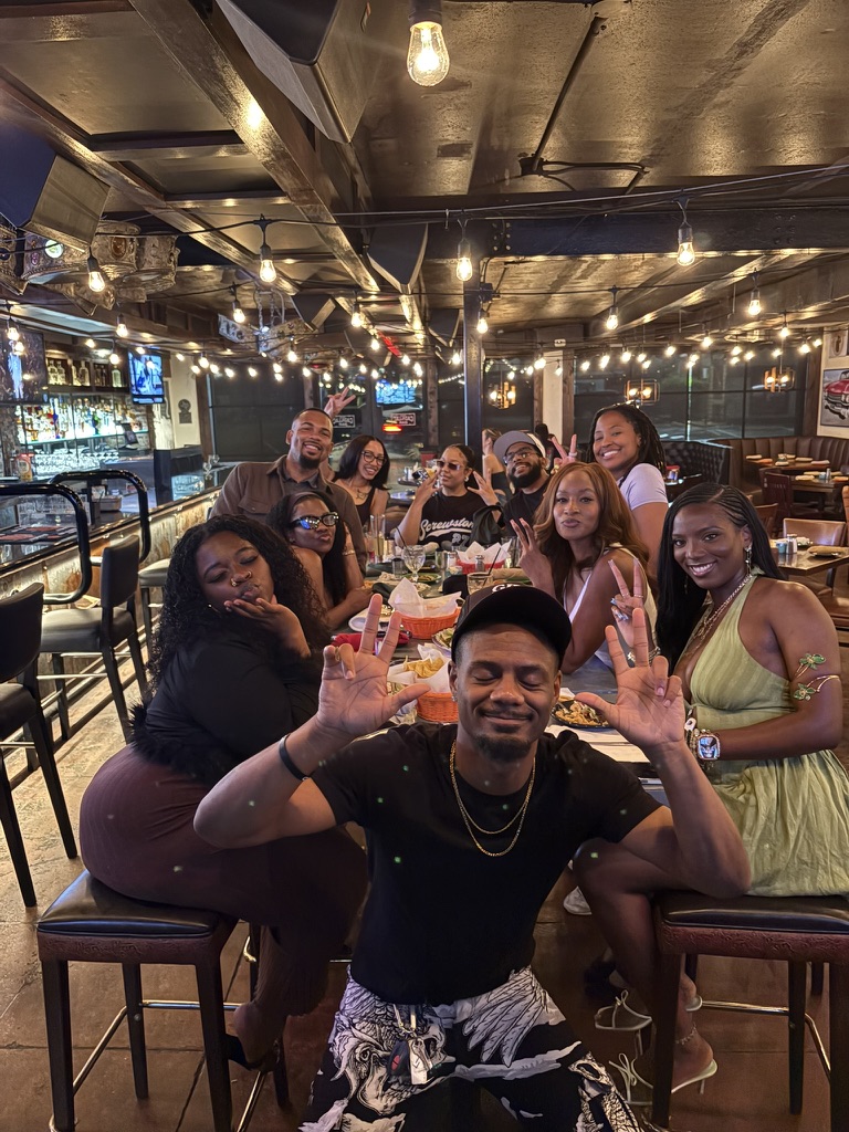 A big group dinner with members smiling and throwing up peace signs
