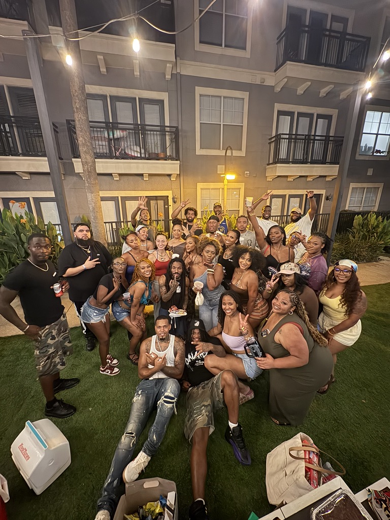 A backyard cookout with dozens of members posing together on the lawn