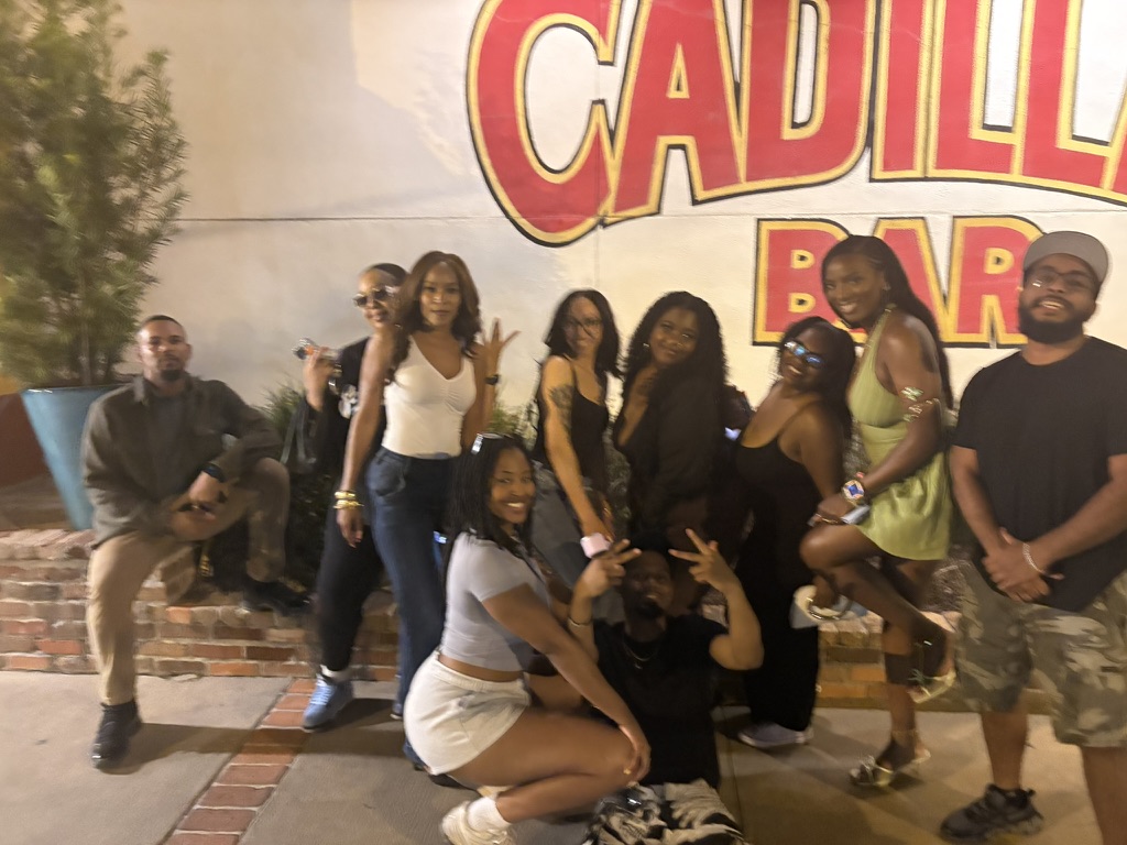 Members lined up in front of the Cadillac Bar wall at night
